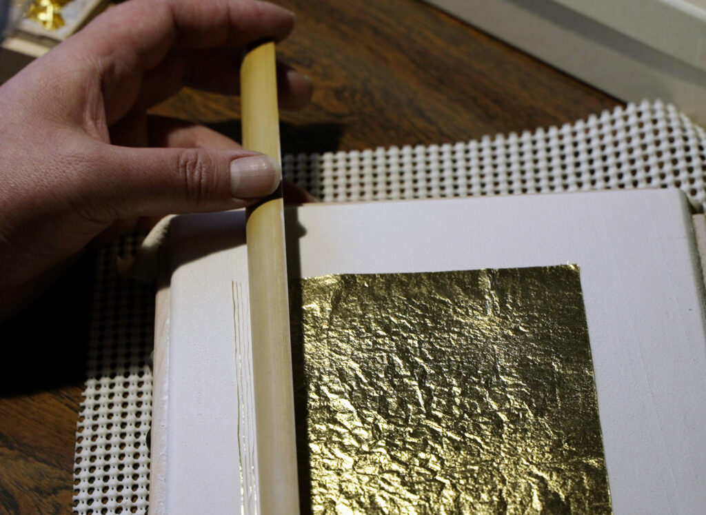 The process of cutting gold leaf into thin strips with a bamboo knife