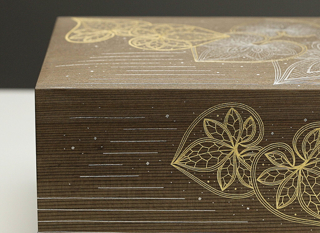 The beautiful kirikane pattern of twin-leaf hollyhock elegantly applied to the lid of a Jindai-sugi box