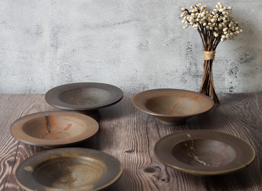 Wood-fired ceramic dishes and a dried flower arrangement on a weathered wooden table — Life with Kogei